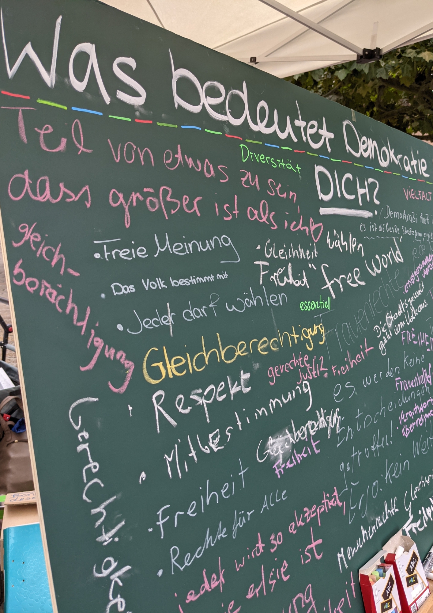 bunt beschriebene Kreidetafeln mit kurzen Antworten zu der Frage, was Demokratiebildung für dich bedeutet